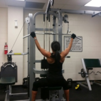 A woman in a gym working out on the cable pull down