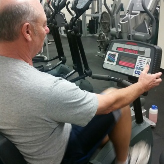 A man in a gym using the stationary cycle machine